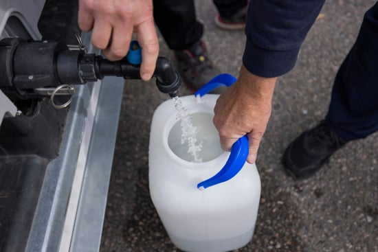 Fyller drickvatten i en vattendunk